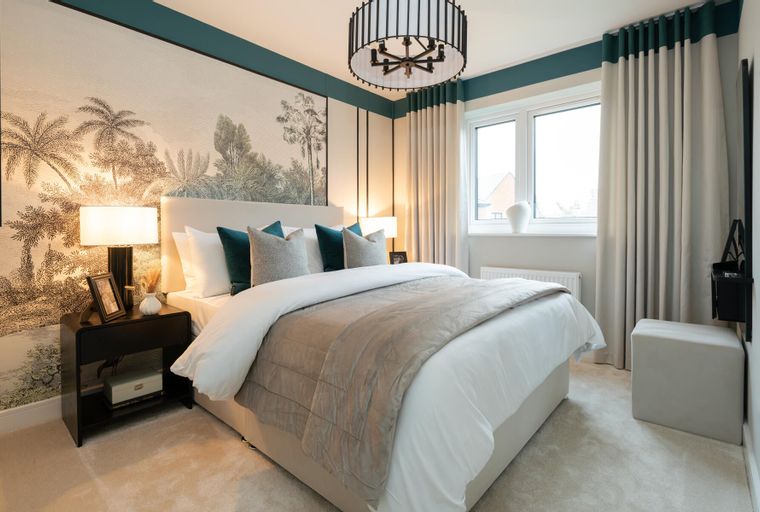 A bedroom with a bed, pillows, lamps, and a mural on the wall.