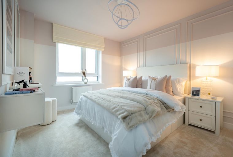 A bedroom with a bed, bedside tables, and a window.