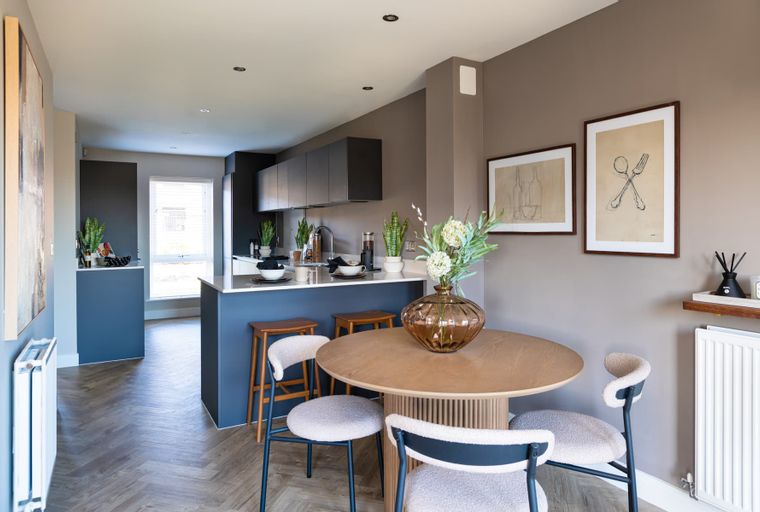 A dining area and kitchen with a round table, chairs, and a kitchen island.