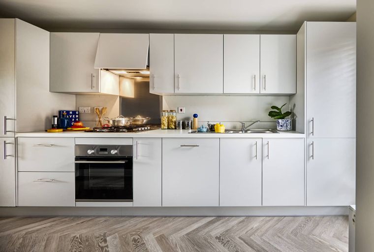 A modern kitchen with white cabinets, a built-in oven, and a gas hob.