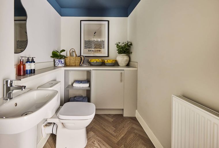 A bathroom with a toilet, sink, and storage cabinet.