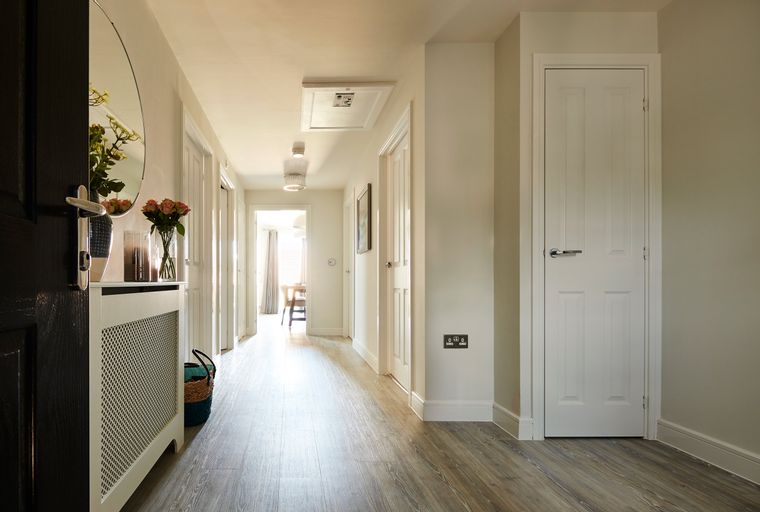 A hallway with multiple doors, a radiator cover, a mirror, and wood-effect flooring.