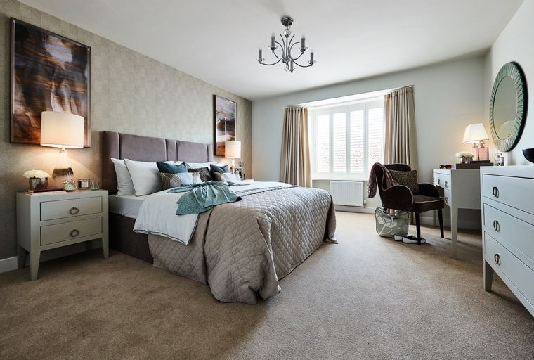 A bedroom with a bed, bedside tables, a dressing table, and a chair.