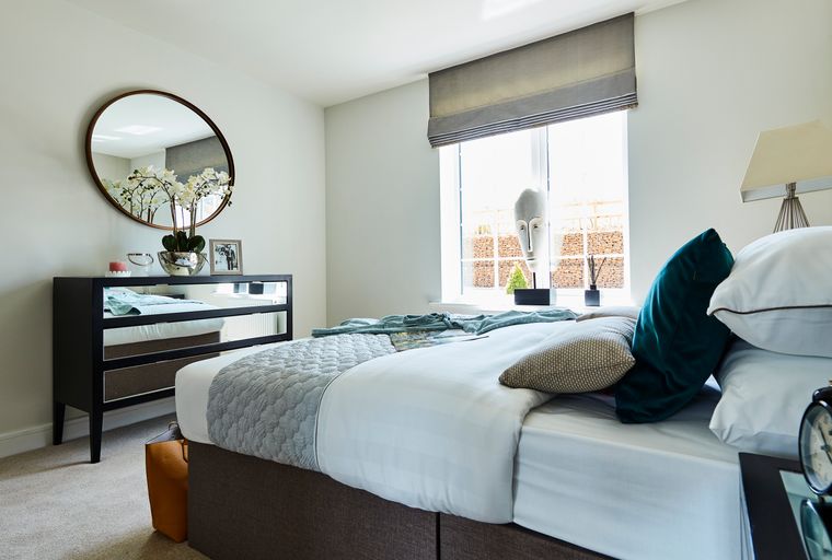 A bedroom with a bed, dresser, and a mirror.