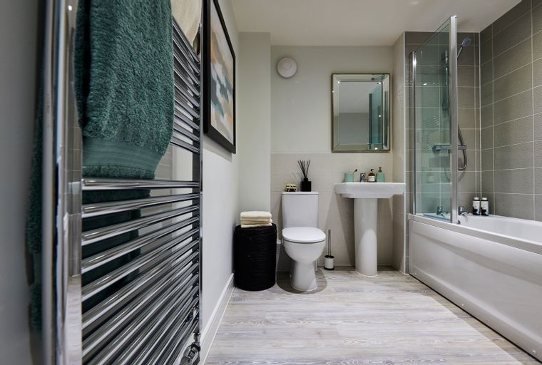 A bathroom with a bathtub, shower, toilet, sink, mirror, and towel warmer.