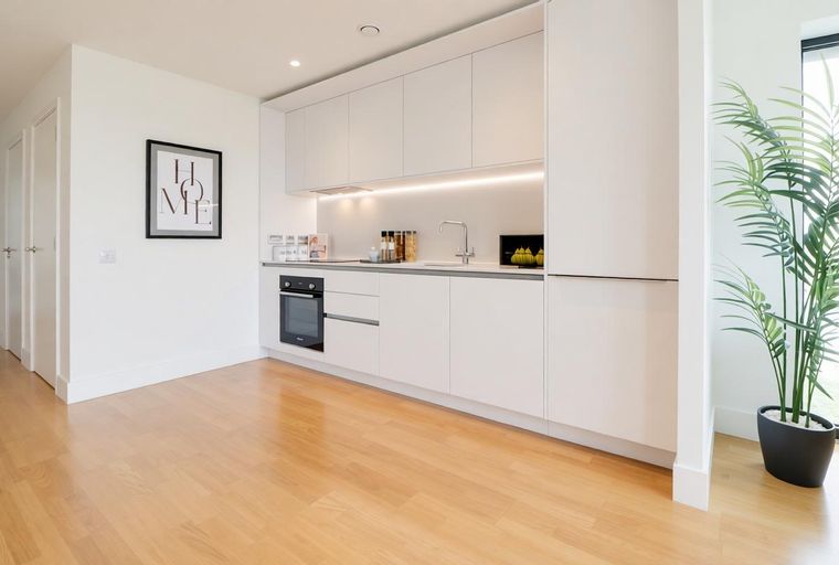 A modern kitchen with white cabinets, an oven, and a sink.