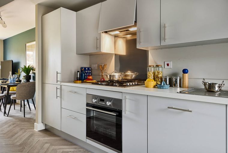 A modern kitchen with light grey cabinets, a built-in oven, and a gas hob.