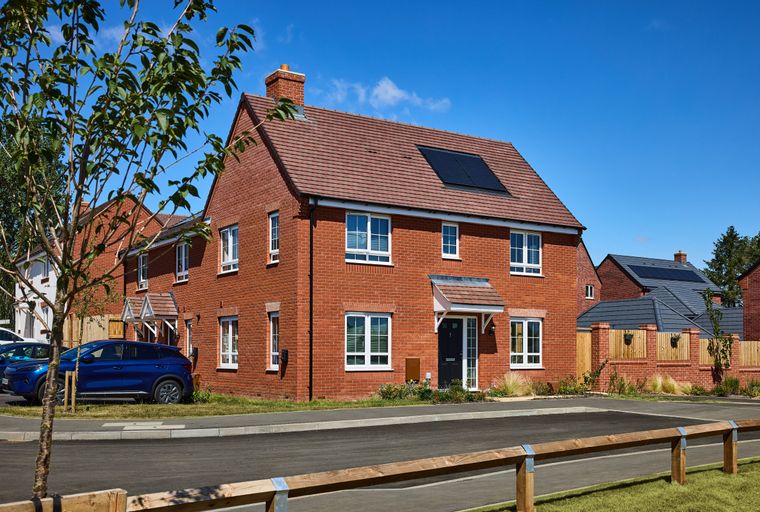 A modern brick house with a tiled roof and solar panels under a blue sky.