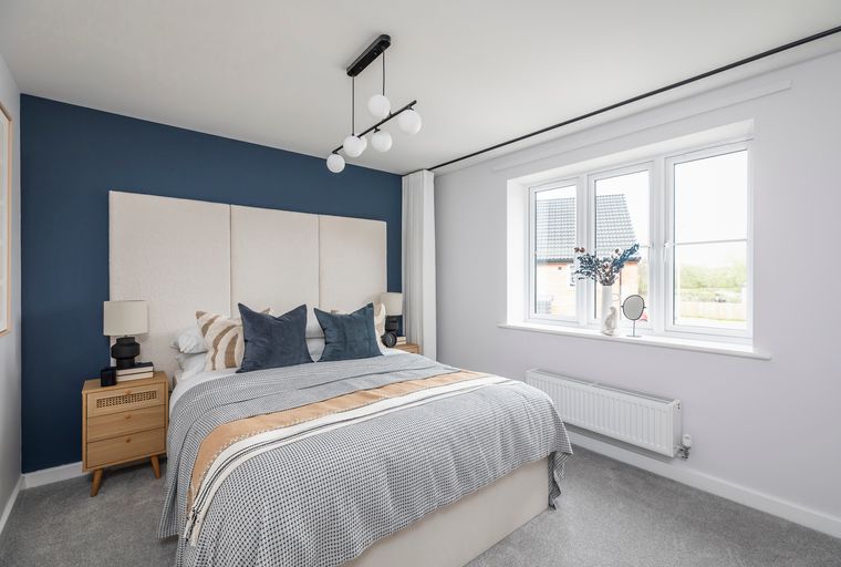 A bedroom with a bed, bedside table, and a window.