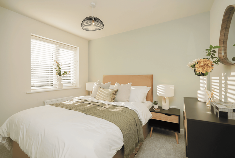 A bedroom with a bed, bedside table, and a window with blinds.
