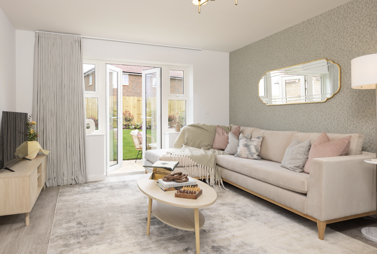 A living room with a sectional sofa, coffee table, and French doors leading to a garden.