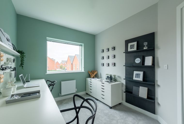 A home office with a desk, chairs, and a window overlooking houses.
