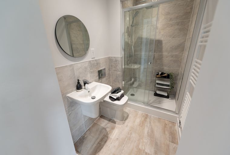 A bathroom with a sink, toilet, and a glass-enclosed shower.