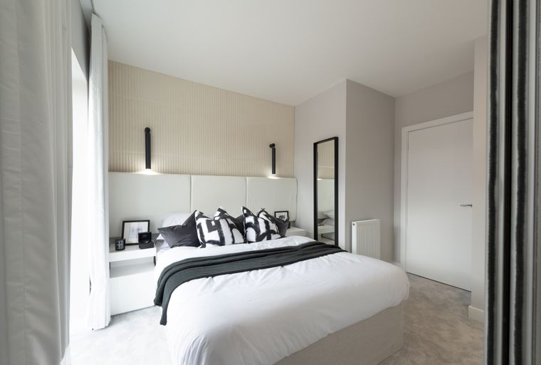 A bedroom with a bed, pillows, and a nightstand.