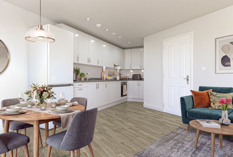 A dining area and kitchen with white cabinets, a round dining table, and a teal sofa.