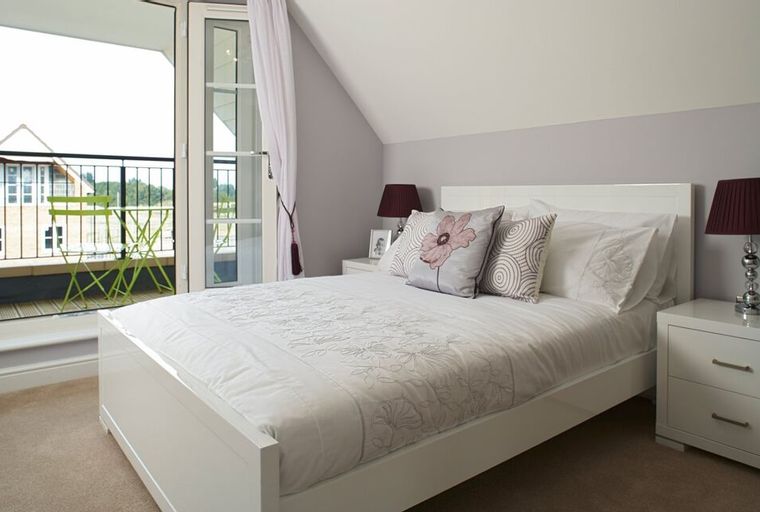 A bedroom with a bed, pillows, and a balcony door.