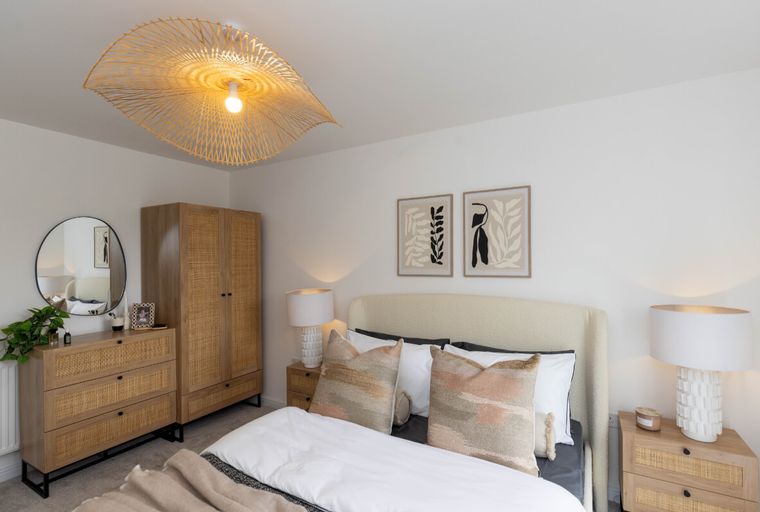 A bedroom with a bed, dresser, wardrobe, and a large pendant light.