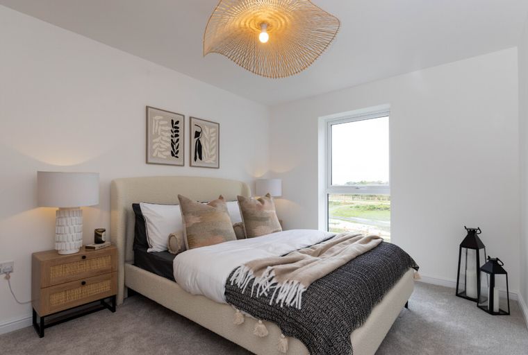 A bedroom with a bed, bedside table, lamp, and artwork.