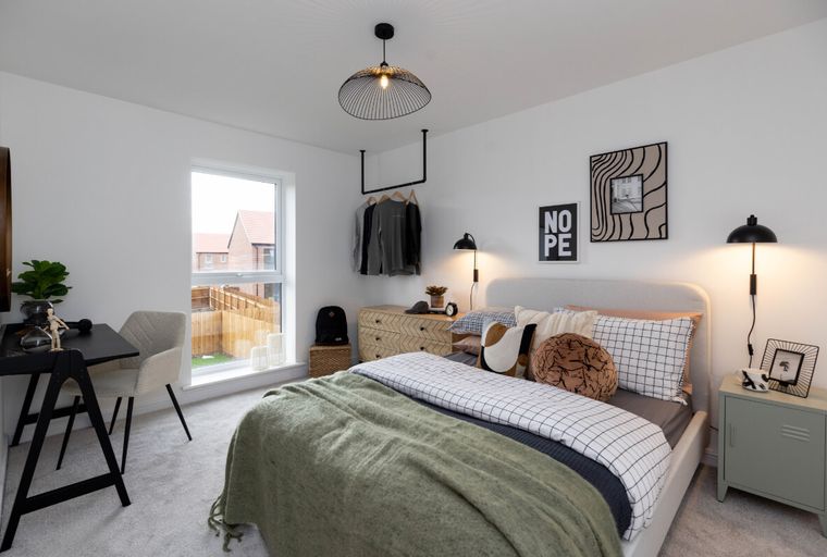 A bedroom with a bed, desk, chair, and window.