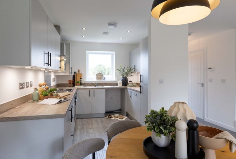 A modern kitchen with grey cabinets, a wooden countertop, and a window.