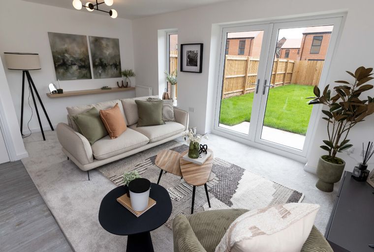 A living room with a sofa, coffee tables, and French doors leading to a backyard.