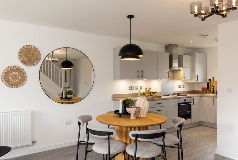 A dining area and kitchen with a round table, chairs, and grey cabinets.