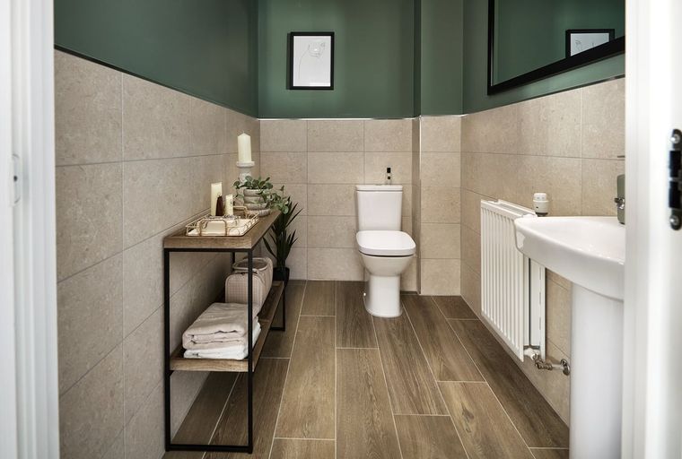 A bathroom with a toilet, sink, shelving unit, and radiator.