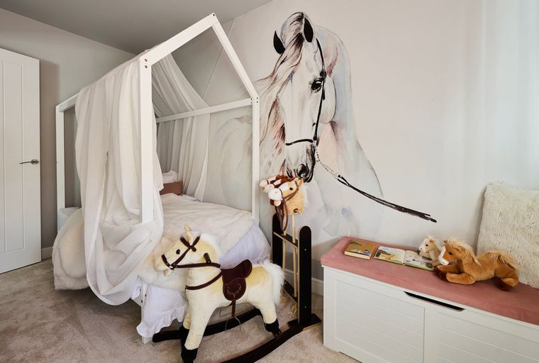 A child's bedroom with a bed, rocking horse, and horse mural.