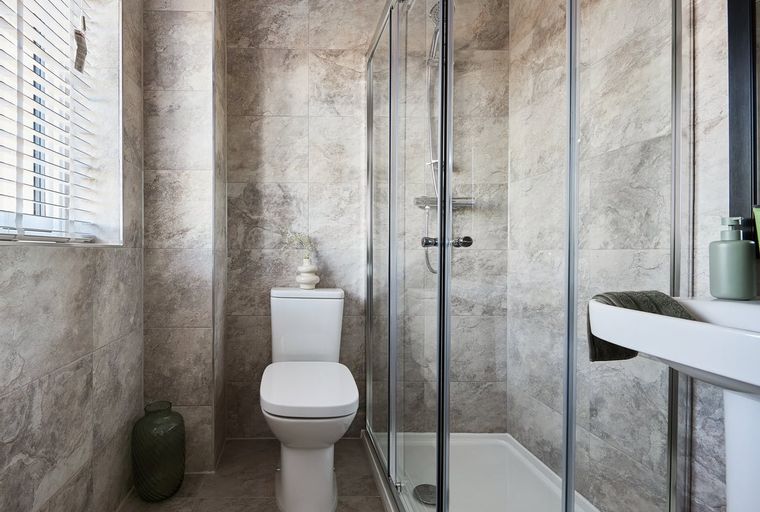 A bathroom with a toilet, a shower, and a sink.