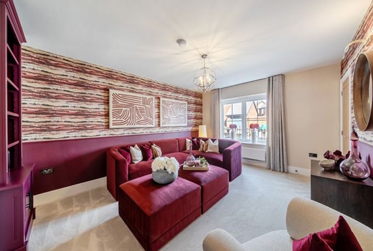 A living room with a red sectional sofa, ottomans, and patterned wallpaper.