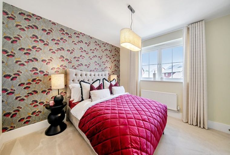 A bedroom with a bed, patterned wallpaper, and a window.
