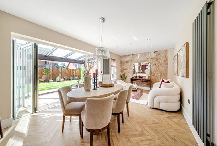 A dining room with a table, chairs, and bi-fold doors leading to a garden.