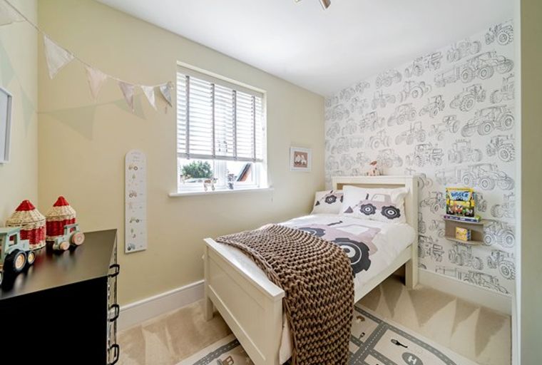 A child's bedroom with a bed, dresser, and tractor-themed wallpaper.