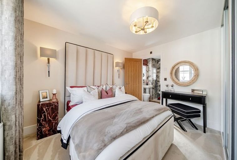 A bedroom with a bed, headboard, bedside tables, vanity, and mirror.