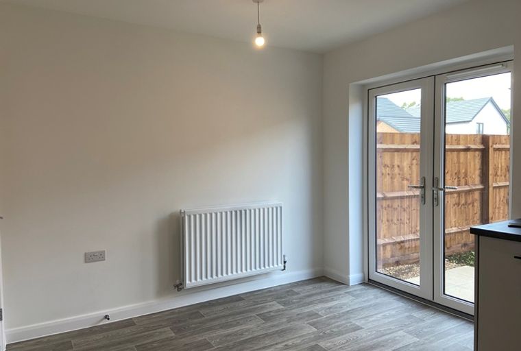 A dining area with a radiator, electrical socket, French doors, and wood-effect flooring.