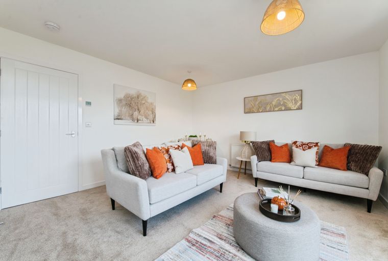 A living room with two sofas, an ottoman, and decorative pillows.