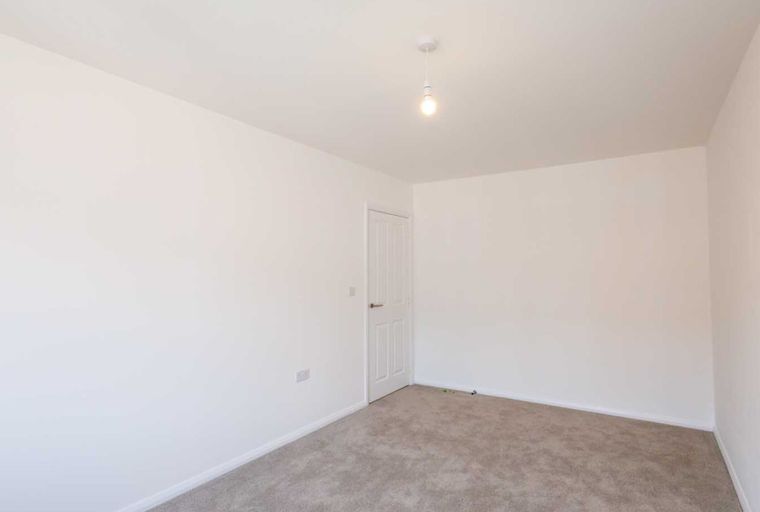 A room with white walls, a white door, and a carpeted floor.