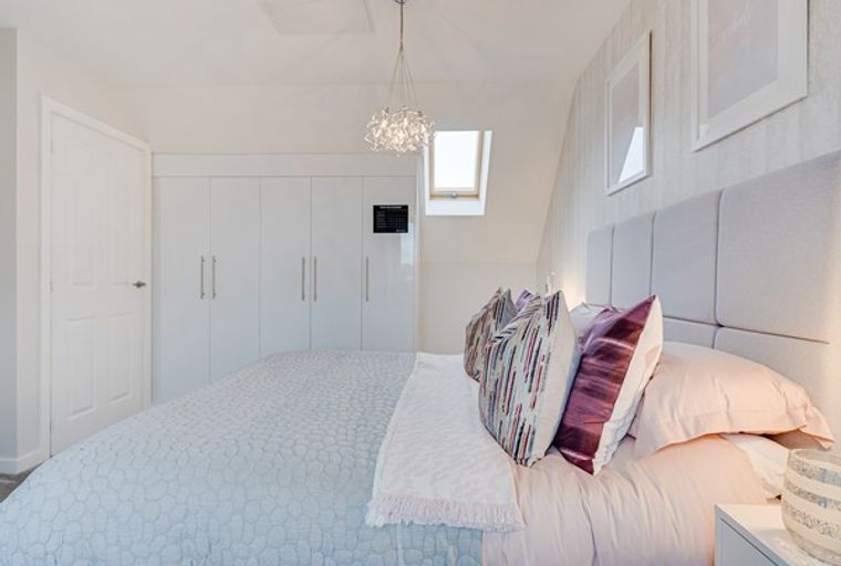 A bedroom with a bed, pillows, and a wardrobe.