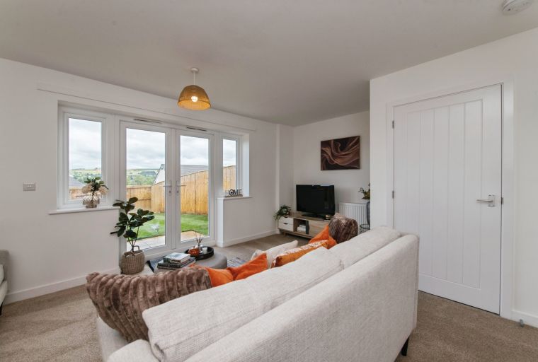 A living room with a sofa, television, and French doors leading to a garden.