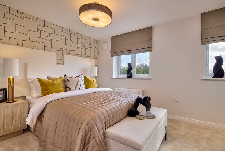 A bedroom with a bed, pillows, lamps, and windows.