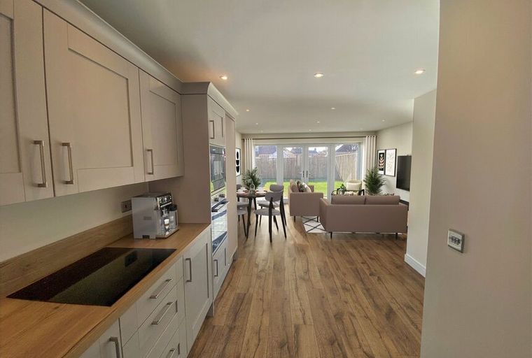 A kitchen and living area with a dining table, sofas, and a backyard view.
