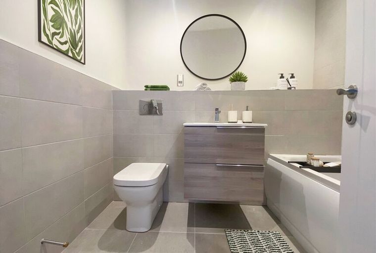 A modern bathroom with a toilet, vanity, and bathtub.