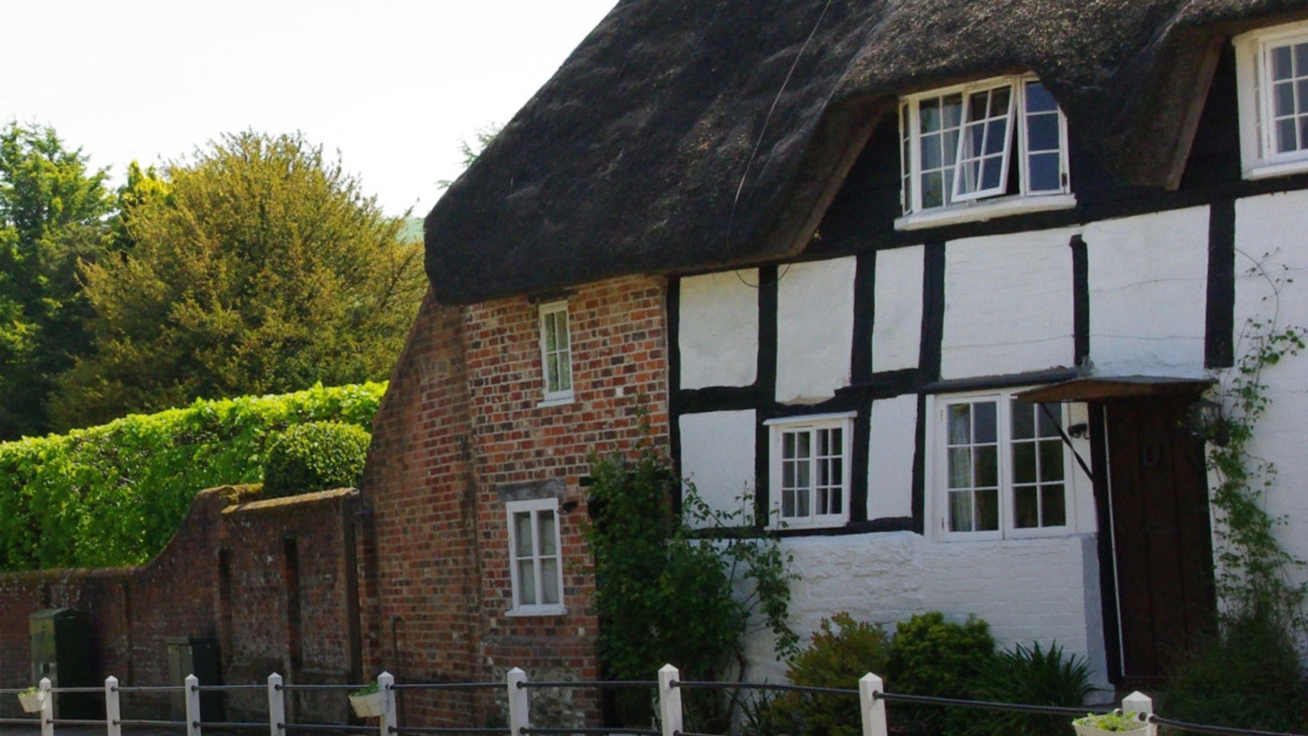 A traditional cottage with a thatched roof and half-timbered walls.