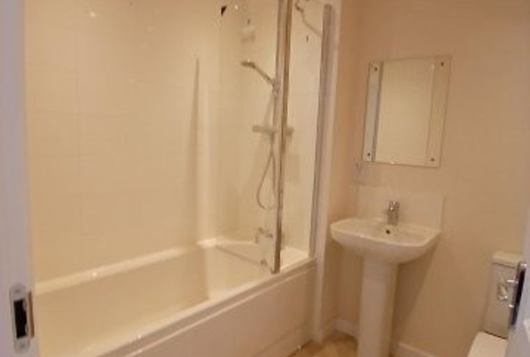 A bathroom with a bathtub, shower, sink, toilet, and mirror.