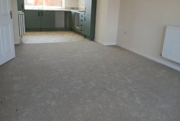 A living room and kitchen area with green cabinets and a large window.