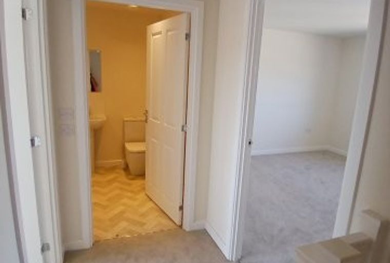 A hallway with doors leading to a powder room and a bedroom.
