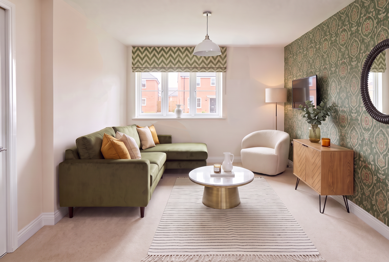 A living room with a green sectional sofa, a coffee table, a rug, and a television.