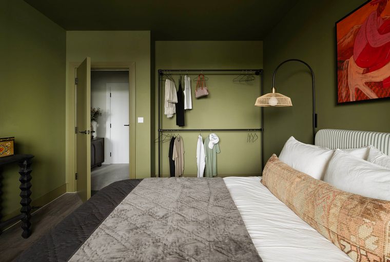 A bedroom with a bed, an open wardrobe, and artwork on the wall.