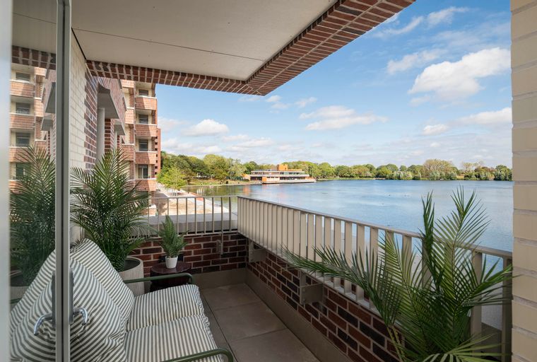 A balcony overlooking a lake with a building in the background.