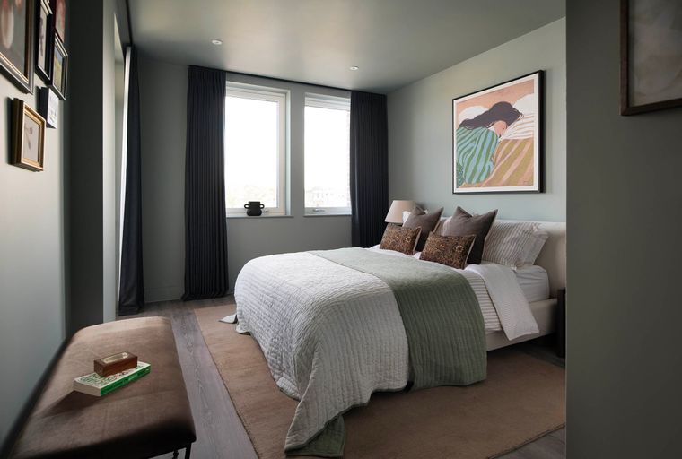A bedroom with a bed, two windows, and a bench.